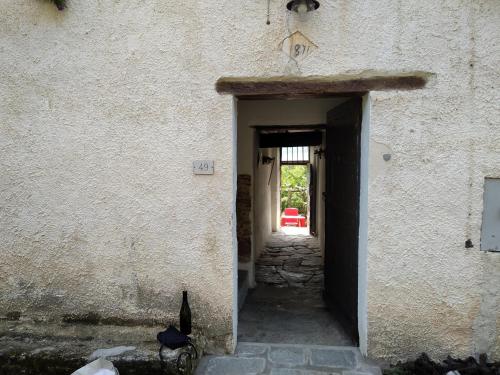 Ca' Rionda - Antica Casa Rurale في Osiglia: باب لمبنى فيه قطه جالسه بالمدخل