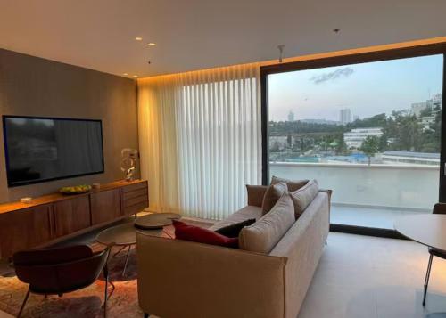 a living room with a couch and a flat screen tv at Amazing 2Bdrm penthouse in JLM with balcony and view - פנטהאוז ירושלים in Jerusalem