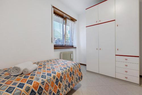 una camera da letto con un letto, armadi bianchi e una finestra di Appartamento Cuore di Comano a Comano Terme