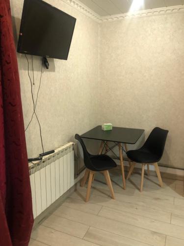 a table with two chairs and a television on a wall at Sweet house in Gyumri