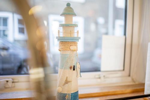 uma estatueta de farol sentada em frente a uma janela em Rockhopper Cottage Lower Largo em Lower Largo