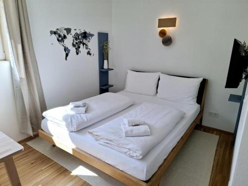 Una cama con sábanas blancas y un mapa del mundo en la pared. en Ferienwohnung Bergufer - Studio im Souterrain, en Oberammergau