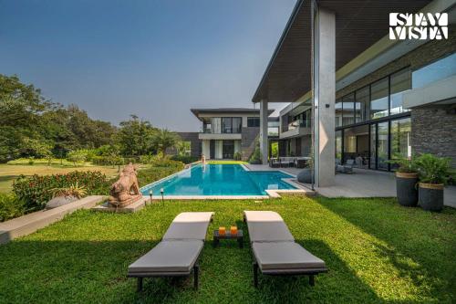 a house with a swimming pool next to a house at StayVista at Acasa with Lawn in Alibaug