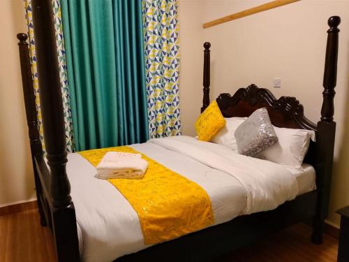 a bed with a wooden frame with pillows on it at Rukeja-PKK Homestays Nanyuki Town in Nanyuki