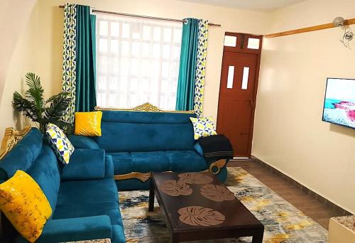 a living room with a blue couch and a table at Rukeja-PKK Homestays Nanyuki Town in Nanyuki