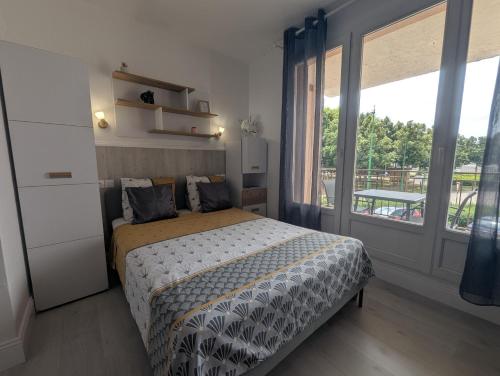 una camera da letto con un letto e una grande finestra di Le bourbon a Bourbonne-les-Bains