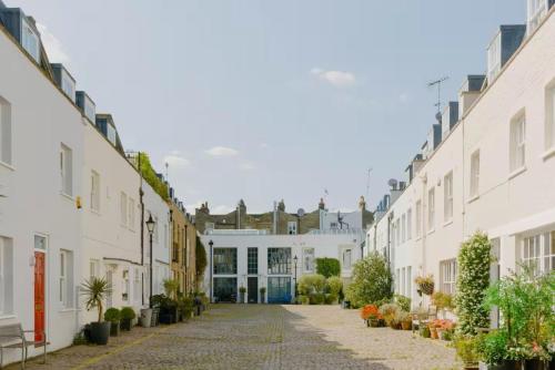 a row of white houses with plants on a street at Haus of Timon Victorian Elegance near Olympia in London