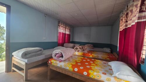 2 camas en una habitación con cortinas rojas en Hotel mardi station, en Astam