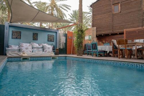 a swimming pool with a couch and a table at Diar Abou Habibi in Tozeur