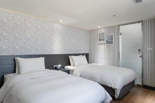 two beds in a hotel room with white sheets at 雋格大飯店 Elence Hotel in Taichung