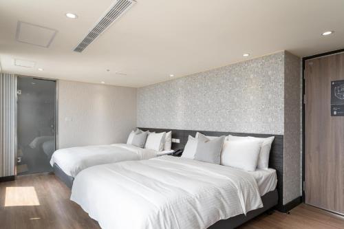 two beds in a hotel room with white pillows at 雋格大飯店 Elence Hotel in Taichung