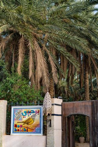 a painting of a bird on a fence next to a palm tree at Diar Abou Habibi in Tozeur