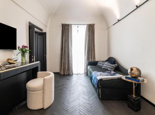 Dimora San Nicola Charming Suite في كونفيرسانو: غرفة معيشة مع أريكة وكرسي