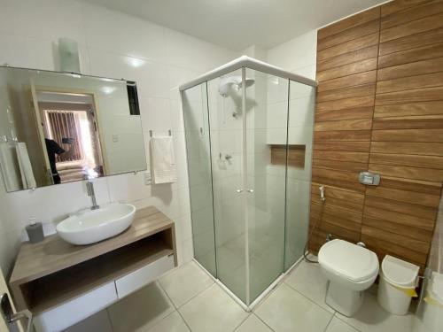 Un baño con ducha, lavabo e inodoro. en Apto Confortável p/ até 9P, 50mts do mar Piçarras, en Piçarras