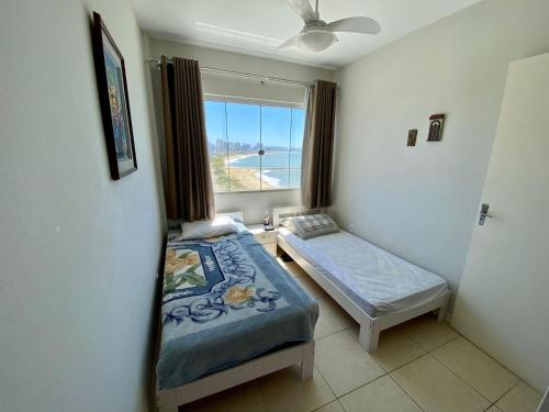 1 dormitorio con 2 camas y una ventana con vistas al océano en Apto Confortável p/ até 9P, 50mts do mar Piçarras, en Piçarras
