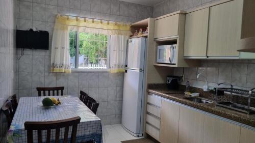a small kitchen with a table and a refrigerator at Casa para 7 Pessoas em Bombas 600 m da Praia in Bombinhas
