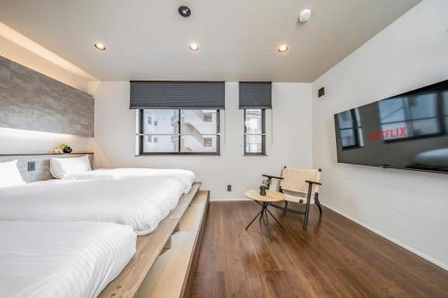 a bedroom with two beds and a flat screen tv at Restia Solace in Sapporo