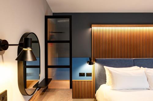 a bedroom with a bed and a mirror at Village Hotel Manchester Ashton in Ashton under Lyne