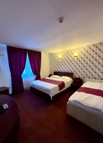 a hotel room with two beds and purple curtains at Hotel Poem Calarasi Ballroom in Călăraşi