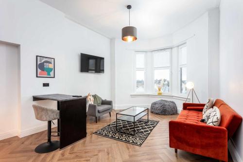 ein Wohnzimmer mit einem roten Sofa und einem Schreibtisch in der Unterkunft The Fairlie Suite No2 in Prestwick