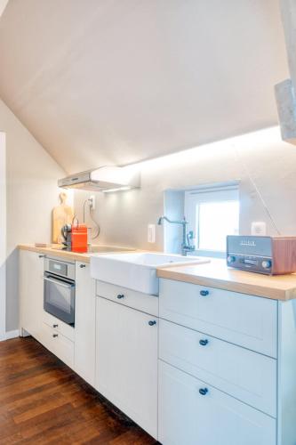 a kitchen with white cabinets and a sink at Cozy apartment with stunning view over the fields in De Haan