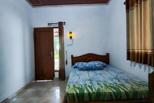a bedroom with a bed with a blue pillow on it at OYO 95055 Homestay Panasan Pak Budi in Kedungtengkong
