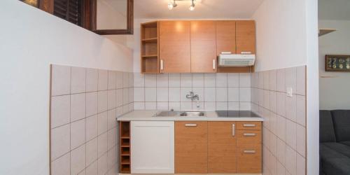 Una pequeña cocina con gabinetes de madera y un fregadero. en Castello, en Mali Lošinj