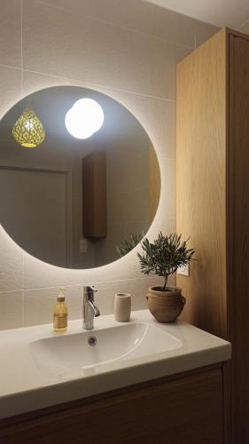 a bathroom with a sink with a round mirror at Logement entier appartement Bischoffsheim in Bischoffsheim