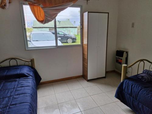 a bedroom with two beds and a window with a car outside at Casa centro in Tolhuin