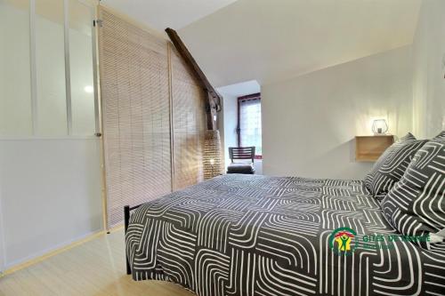 a bedroom with a bed with a black and white comforter at Maison de la vilaine in Saint-Dolay