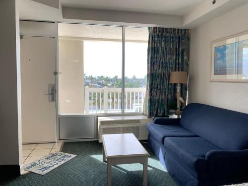 a living room with a blue couch and a large window at Beach Access Elegant Studio near Top Attractions in Daytona Beach