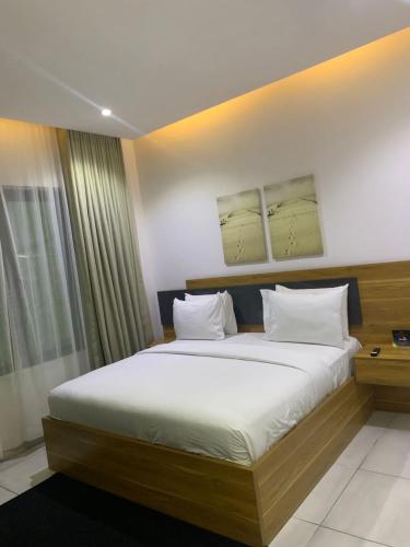 sypialnia z dużym łóżkiem z białymi prześcieradłami w obiekcie The Pelican Lagos w mieście Badore