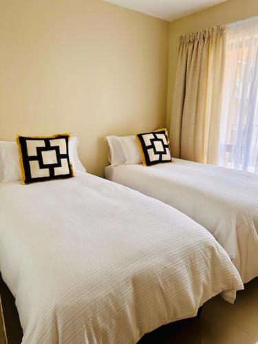 2 witte bedden in een kamer met een raam bij 12th on The Bay in Richards Bay