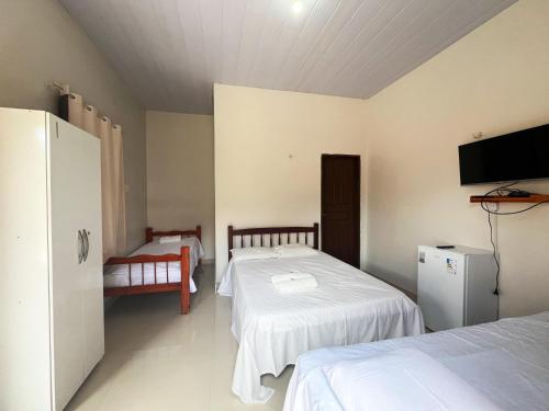 a bedroom with two beds and a flat screen tv at Pousada Sitio Preguicas in Barreirinhas