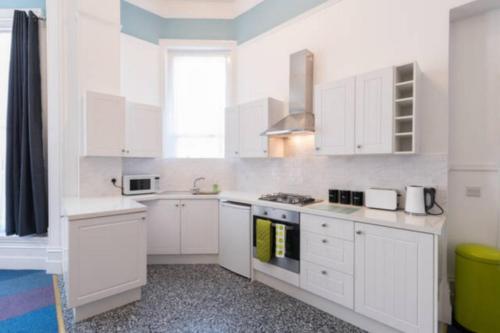 a white kitchen with white cabinets and a sink at Gazeley Manor House - Central Huntingdon in Huntingdon