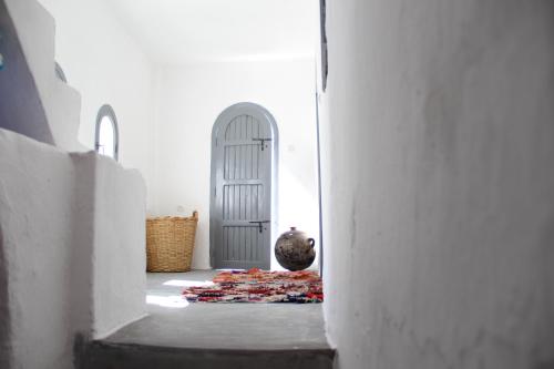 einen Flur mit einer weißen Tür und einer Vase auf einem Teppich in der Unterkunft Dar Jiblia in Chefchaouen