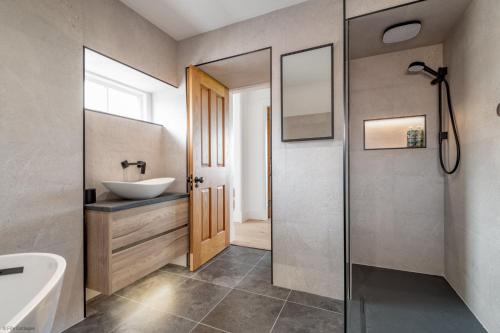 a bathroom with a tub and a sink and a mirror at Caiplie Farmhouse, Caiplie, by Crail, KY10 3JR in Kilrenny