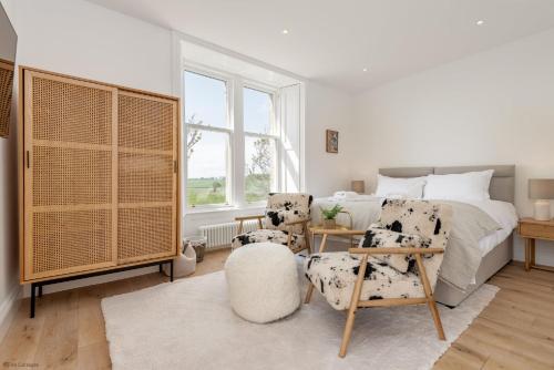 a bedroom with a bed and two chairs and a table at Caiplie Farmhouse, Caiplie, by Crail, KY10 3JR in Kilrenny