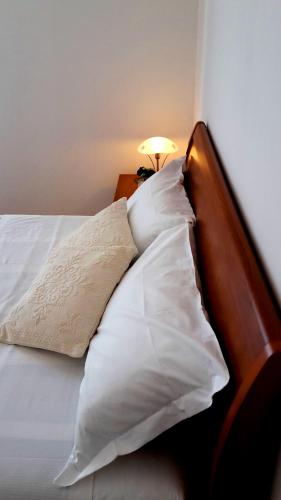 a bed with white pillows and a lamp on a table at Appartamento ai Tigli in Noale