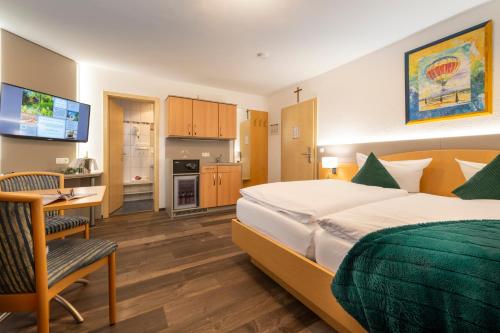 Pokój hotelowy z łóżkiem, biurkiem i kuchnią w obiekcie Hotel Schloßberg w mieście Gräfenberg