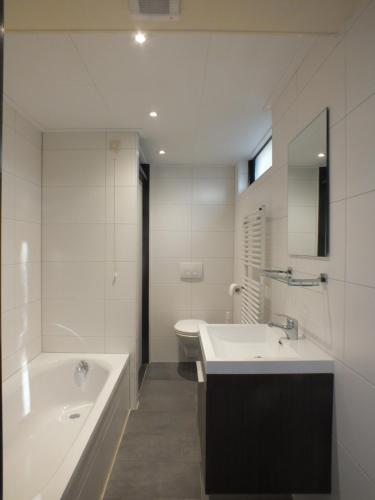 a bathroom with a tub and a sink and a toilet at Camping de Vogel in Hengstdijk
