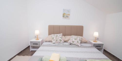 a bedroom with a large bed with two lamps at Tia in Veli Lošinj
