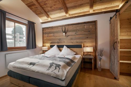 una camera da letto con un letto con una parete in legno di das brunn - Luxus Chalet a Kirchberg in Tirol