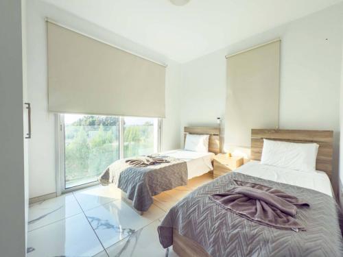 een slaapkamer met twee bedden en een groot raam bij Alassia Blue Villa in Protaras