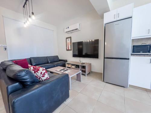 a living room with a couch and a refrigerator at Pernera Seaside Villa - Sun, Sea, Poolside Bliss in Protaras
