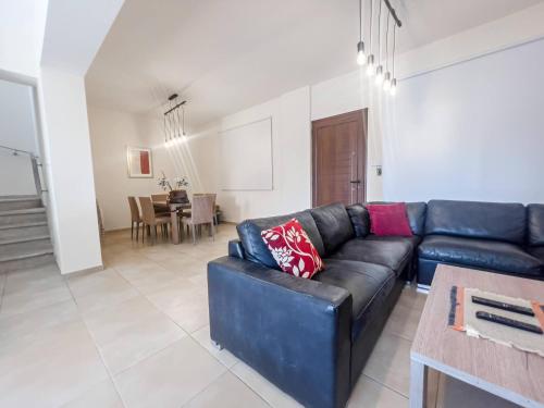 a living room with a black leather couch and a table at Pernera Seaside Villa - Sun, Sea, Poolside Bliss in Protaras