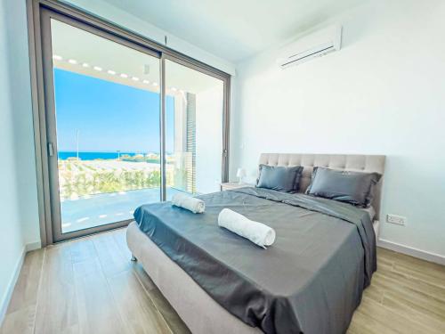 a bedroom with a large bed with a large window at Azure Villas by Marc in Paralimni