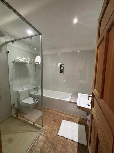 a bathroom with a glass shower and a tub and a sink at Dar Al Miraaj in Rabat