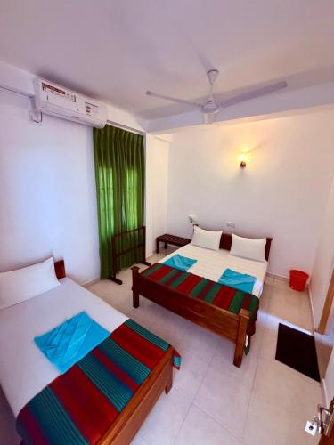 a bedroom with two beds and a window at Vishmee Holiday Inn in Embilipitiya