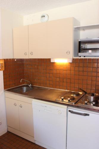une cuisine avec des armoires blanches et un évier dans l'établissement Trois Vallées Appartements VTI, à Val Thorens